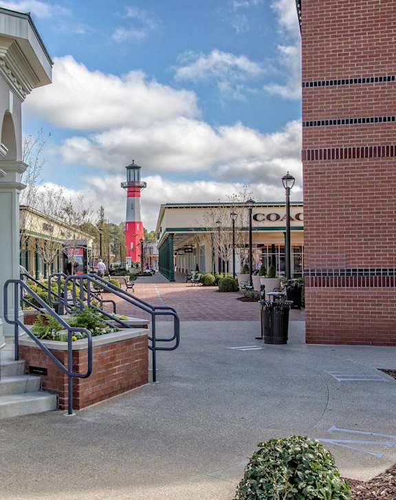 A lighthouse is in the distance behind a white arched building.