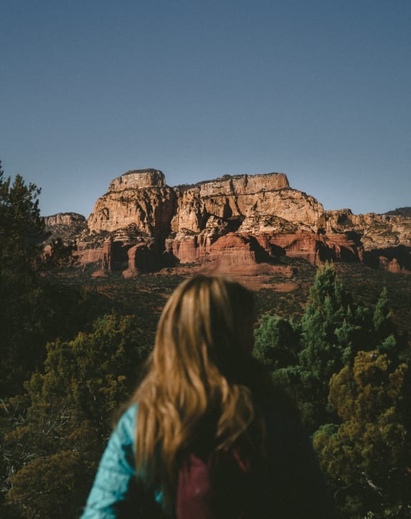 a woman looking at a rock formation in the desert