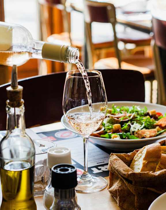 A bottle of white wine is being poured into a glass.