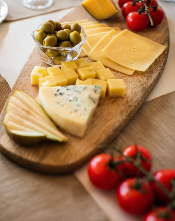 a wooden table topped with a variety of cheese and olives