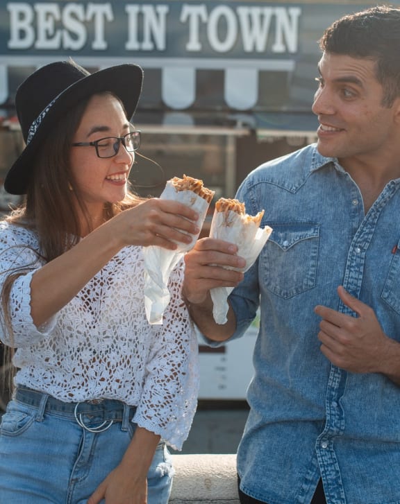a man and a woman eating sandwiches at a food truck