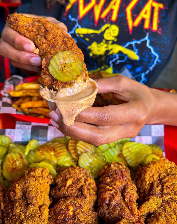 a person holding up a sandwich with a bite taken out of it