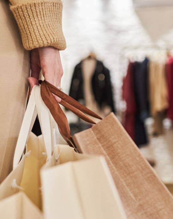 woman standing in front of a store window holding a bag