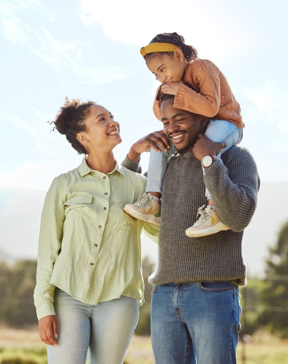 a man and woman holding a child on their shoulders
