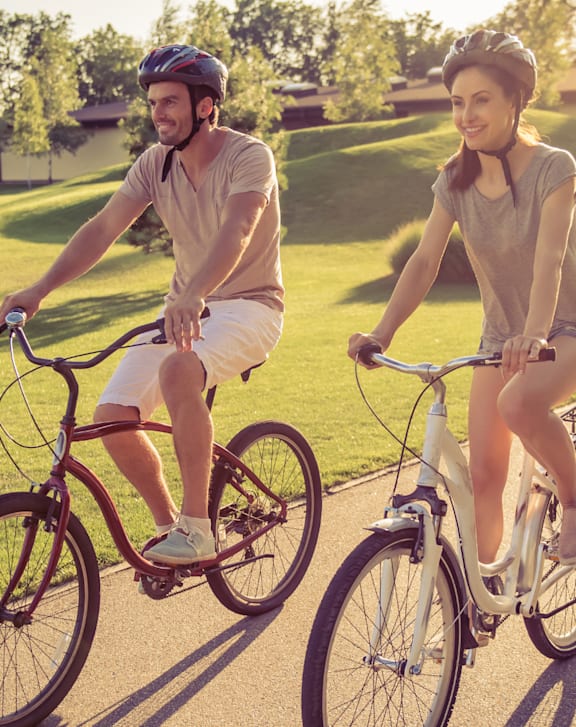 Two people riding bicycles on a sunny day.