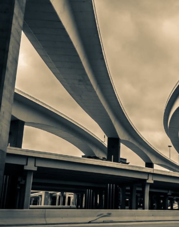 A black and white image of a modern overpass structure.