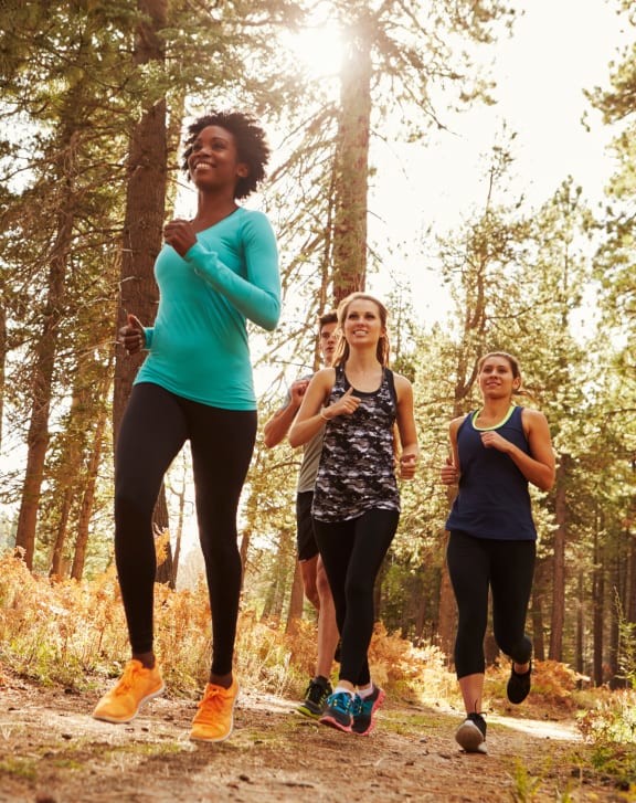three women running through the woods on a trail