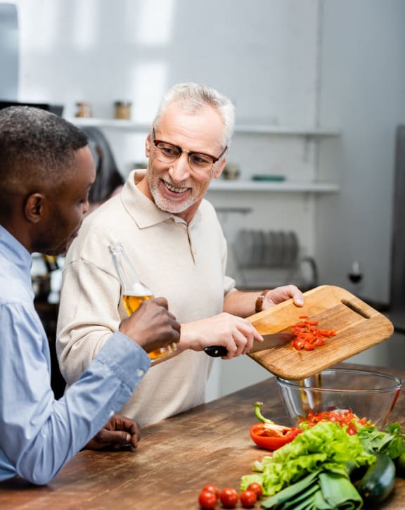 a man and a man cutting up vegetables on a cutting board