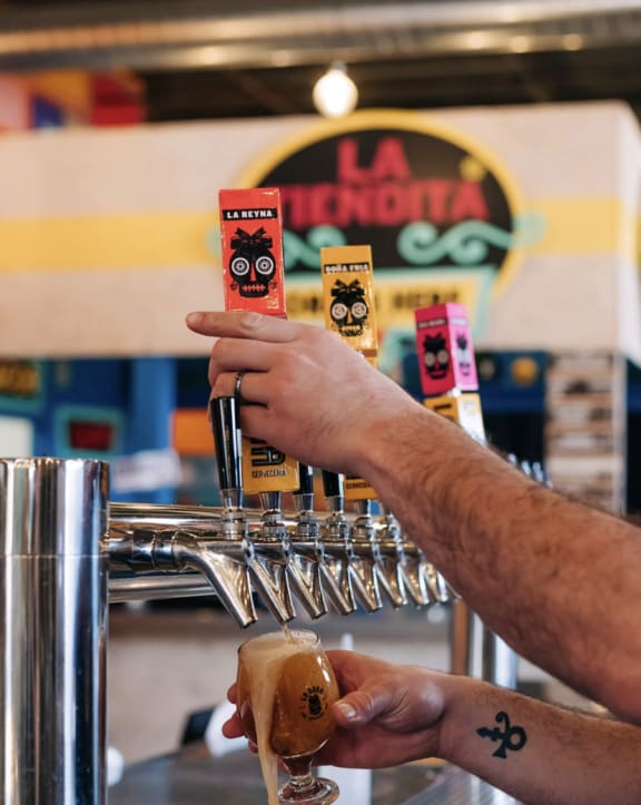 a person is holding a container of beer and a hot dog