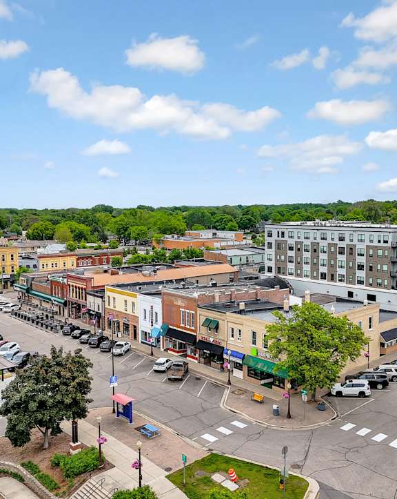 A street view of a town with a red car parked on the side of the road.