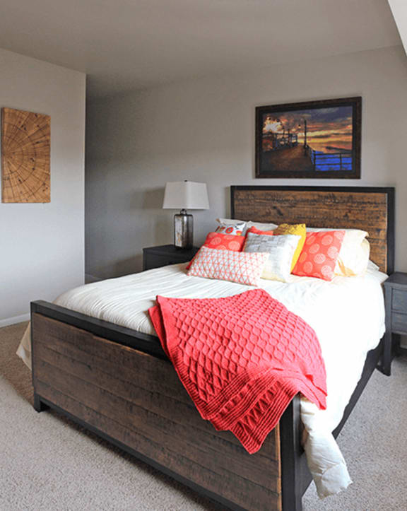 a bedroom with gray walls and a bed with red and yellow pillows