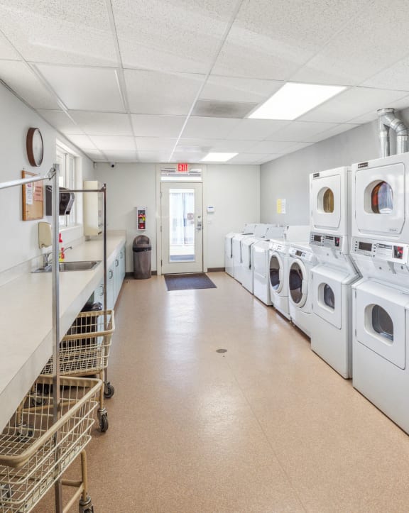 a laundromat with a row of washes and dryers in a room