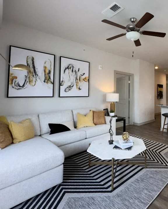 A living room with a white couch, a coffee table, and two abstract paintings on the wall.