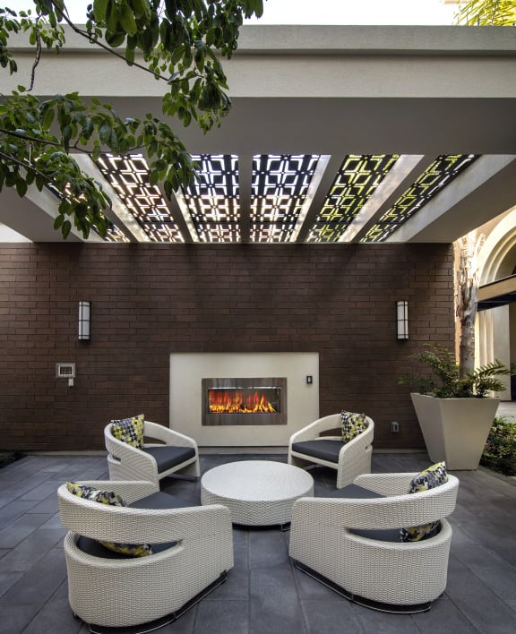 A patio with a fireplace and chairs. at West Park Apartments, San Diego, CA