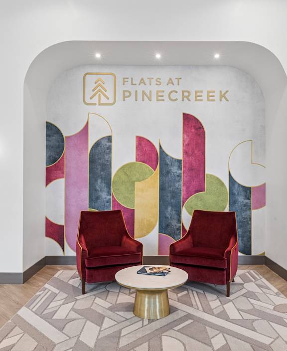 A brightly colored mural with the words "Flatats at Pinecreek" is displayed on a white wall.