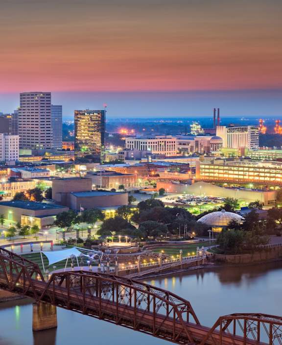 A cityscape at dusk with a bridge crossing a river.