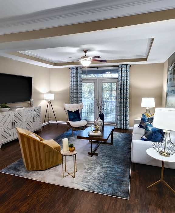 A living room with a brown chair, a white couch, and a television on the wall.