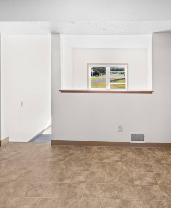 A room with a brown tile floor and a painting on the wall.