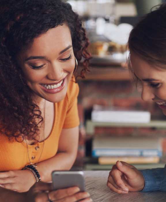 Two women are looking at a smartphone together.