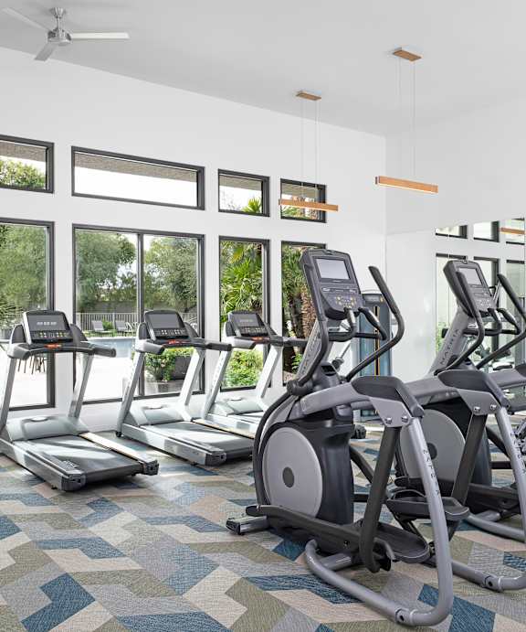 A gym with treadmills, exercise bikes, and a television.