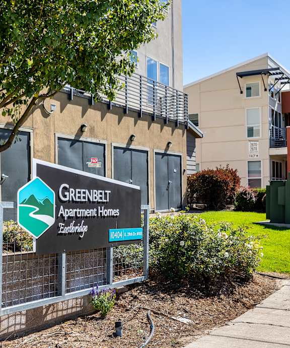 A sign for Greenbelt Apartment Homes stands in front of a building.
