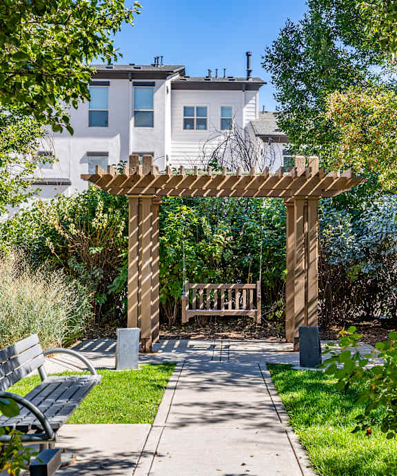 A wooden archway leads to a white building with a balcony.