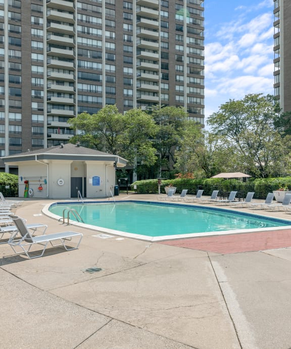 a pool with chaise lounge chairs and umbrellas at the enclave at woodbridge apartments