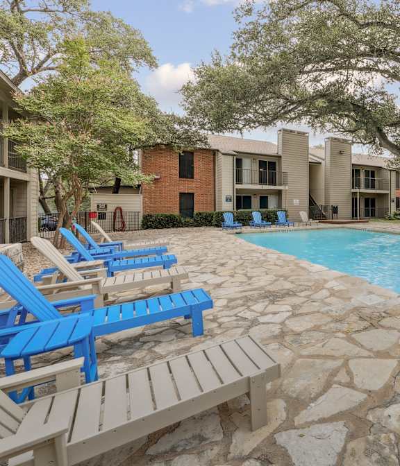 A pool surrounded by blue chairs and a stone wall.