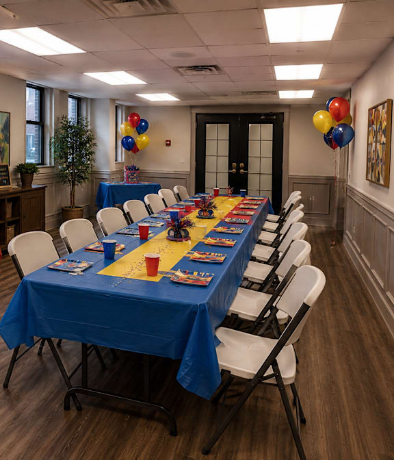 A room with tables set up for a party with red and blue tablecloths.