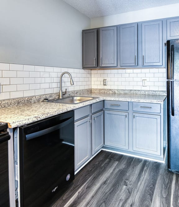 an empty kitchen with blue cabinets and granite counter tops and a sink at Ashford Place Apartments, North Carolina, 28081