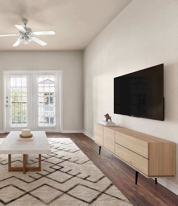 A living room with a white couch, a coffee table, and a flat screen TV mounted on the wall.