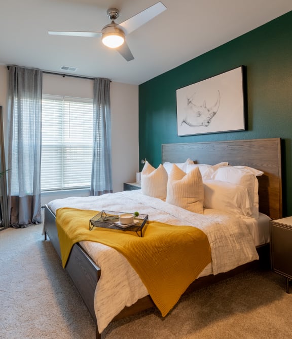 a bedroom with a green accent wall and a yellow bedspread