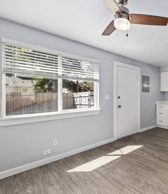 an empty kitchen with a large window and a ceiling fan