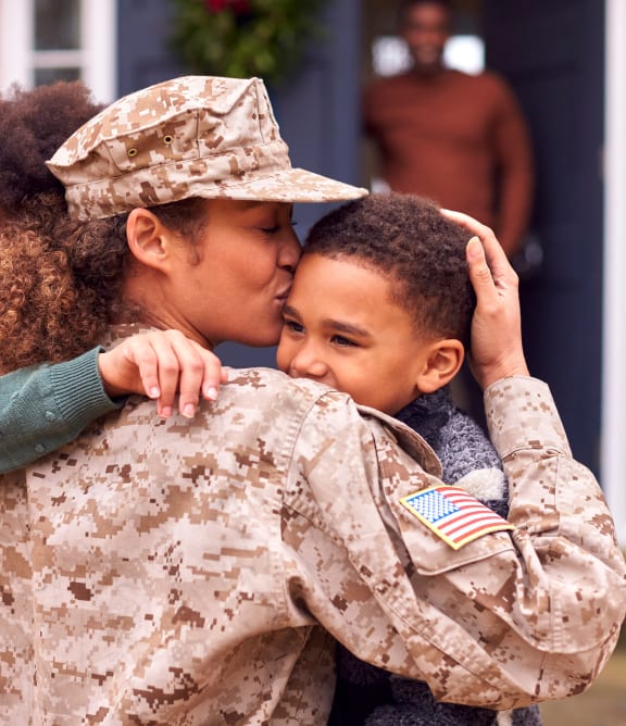 a woman in a military uniform is kissing a soldier on the cheek