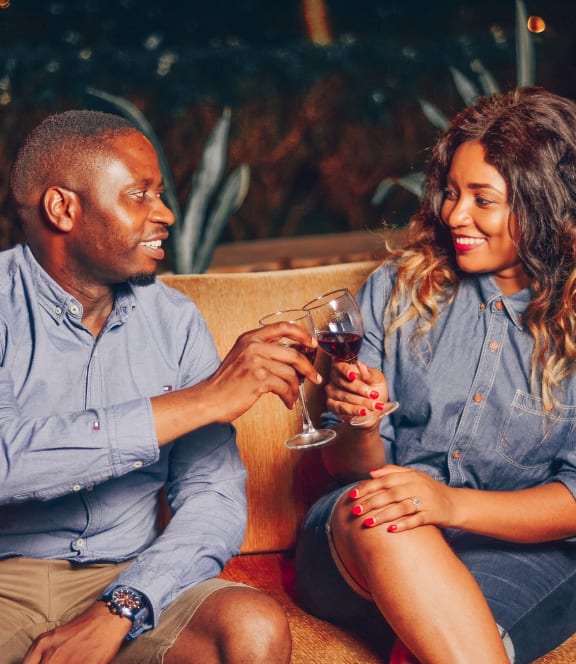 a man and woman sitting on a couch drinking wine
