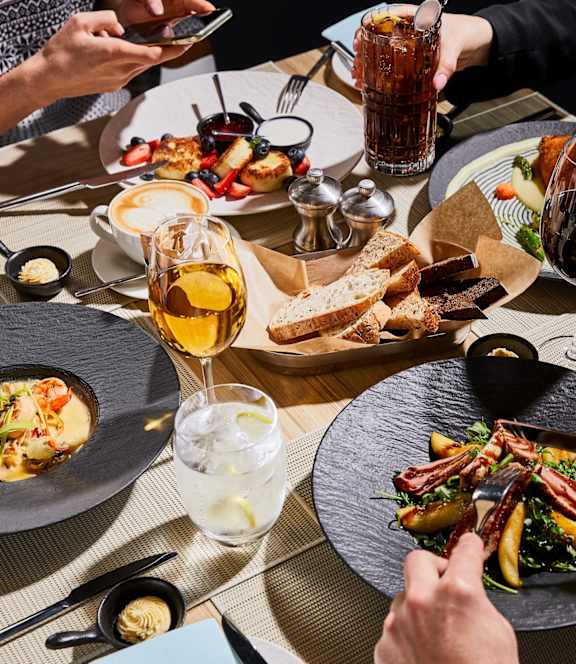 A group of people are dining at a restaurant with plates of food in front of them.