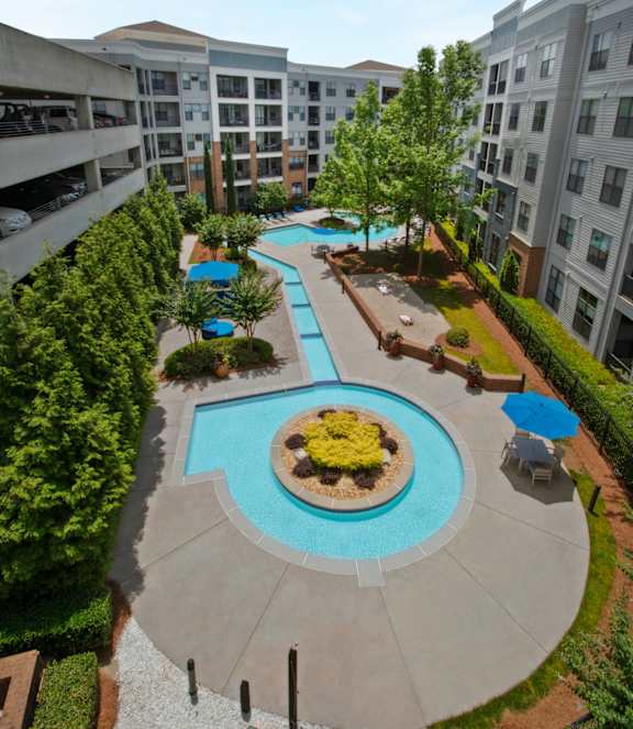 A round pool surrounded by trees and chairs.