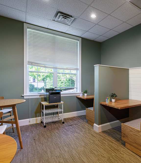 A room with a table, chairs, and a laptop on a cart.