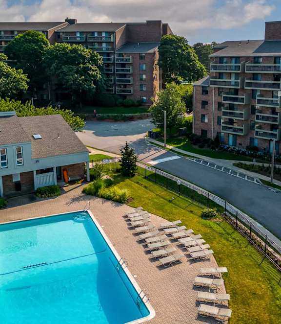 A swimming pool surrounded by sun loungers in a residential area.