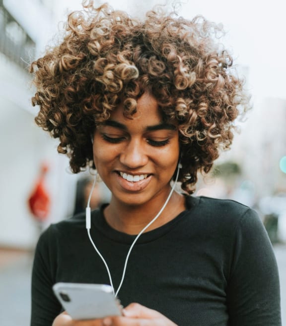 a woman looking at her cell phone while wearing headphones