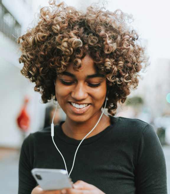 a woman looking at her cell phone while wearing headphones