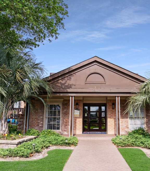 the front of a brick building with palm trees