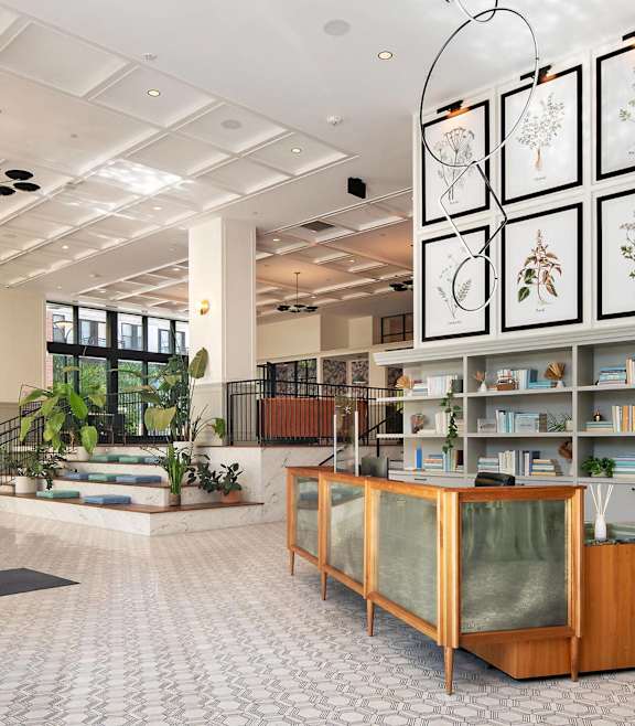 a lobby with a reception desk and a large gallery of flowers on the wall