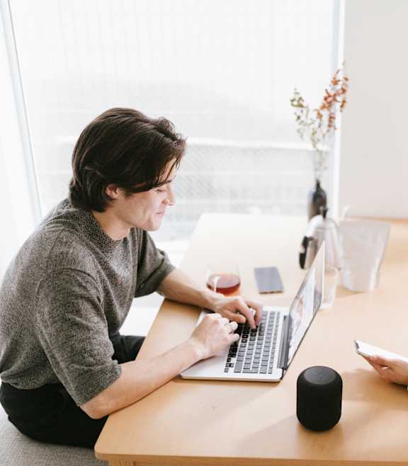 Two people sitting at a table with a laptop.