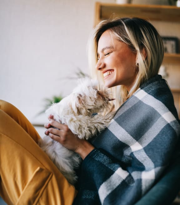 a woman sitting on a couch holding a dog