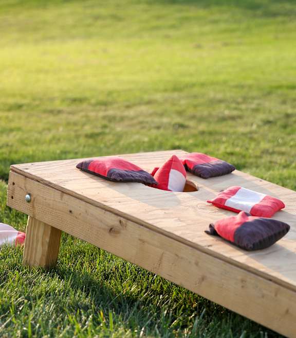A wooden bench with red and white pillows on it.