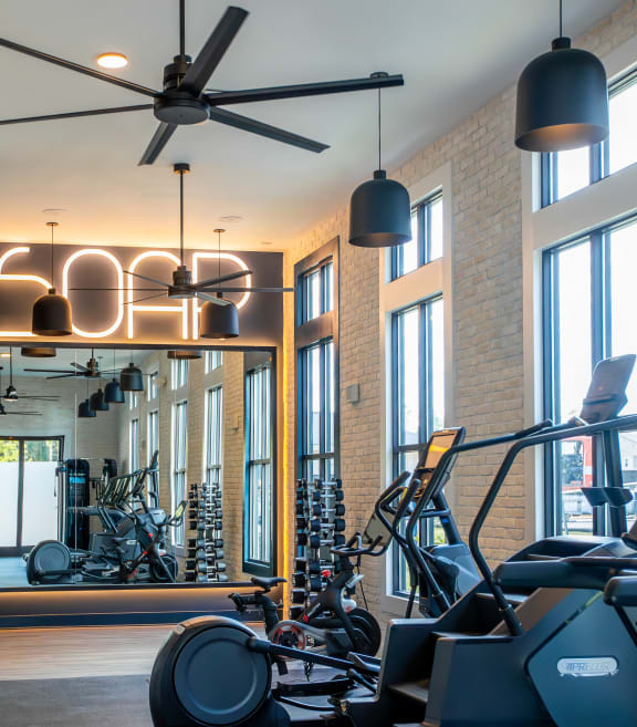 a gym with various exercise machines and a ceiling fan
