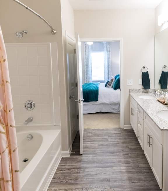 A bathroom with a white tub and a bed in the background.
