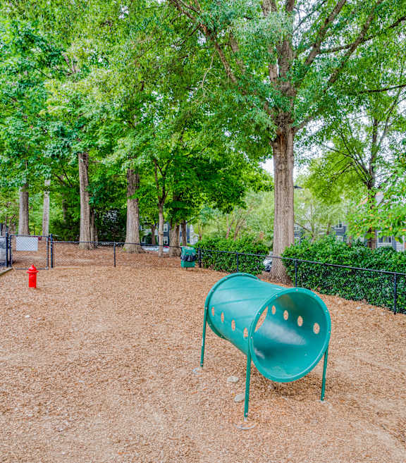 A playground with a green slide and a red fire hydrant.
