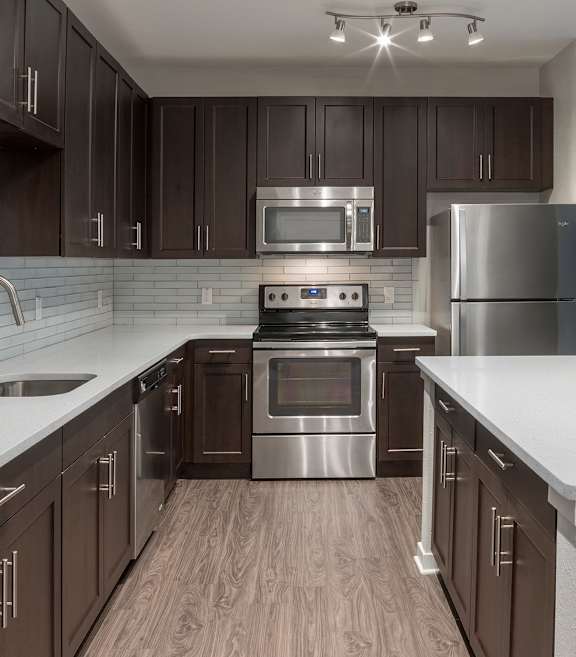 A modern kitchen with dark brown cabinets and stainless steel appliances.